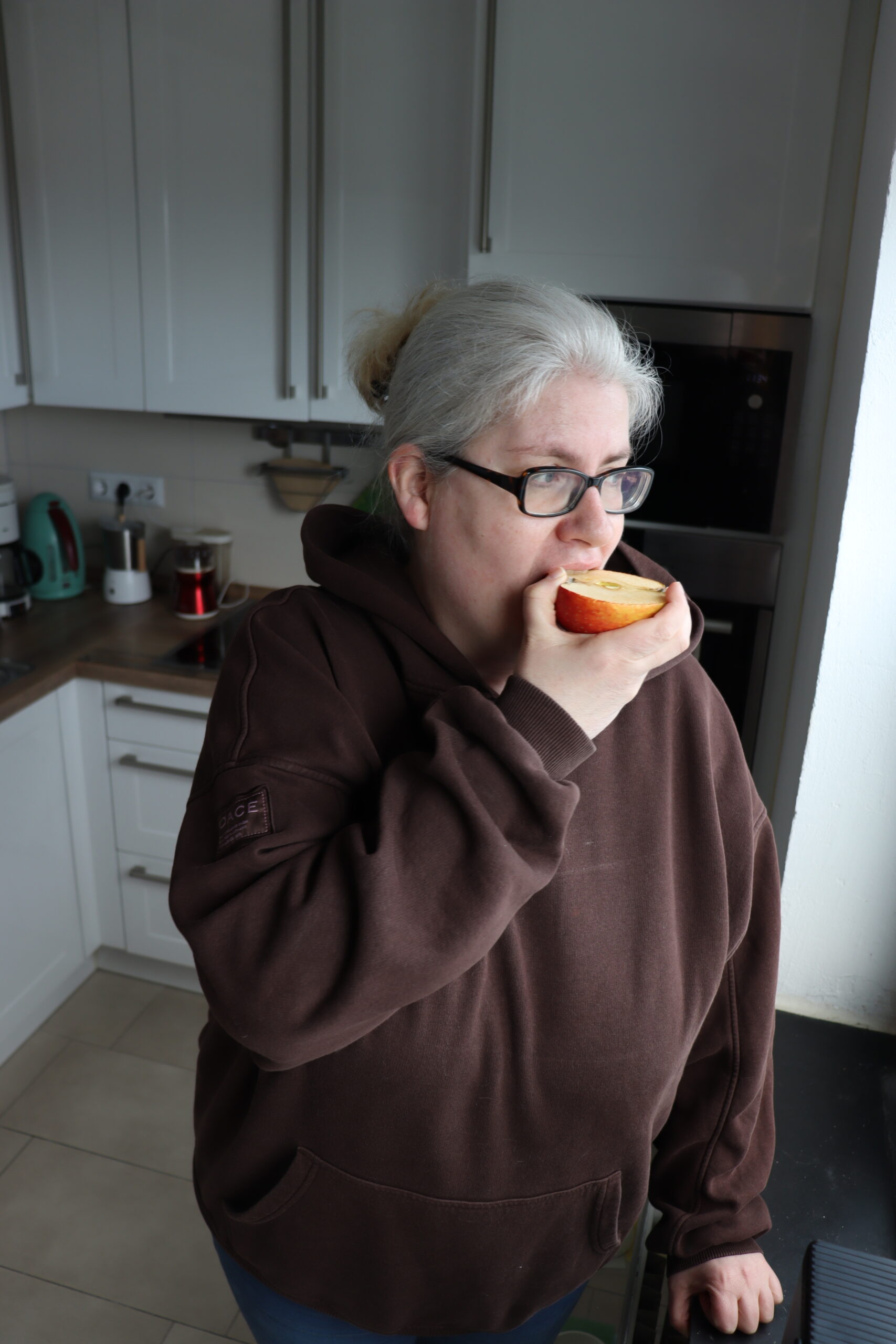 Barbara Hoesmann isst einen Apfel in ihrer Küche